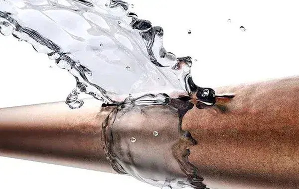 Wasser schießt aus einem gerissenen Kupferrohr
