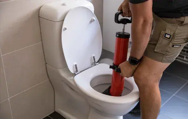 Installateur setzt eine Druckpumpe an einer verstopften Toilette an